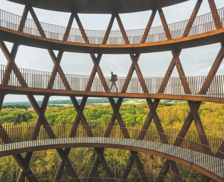 A man walks up Camp Adventure, a forest tower in Denmark.